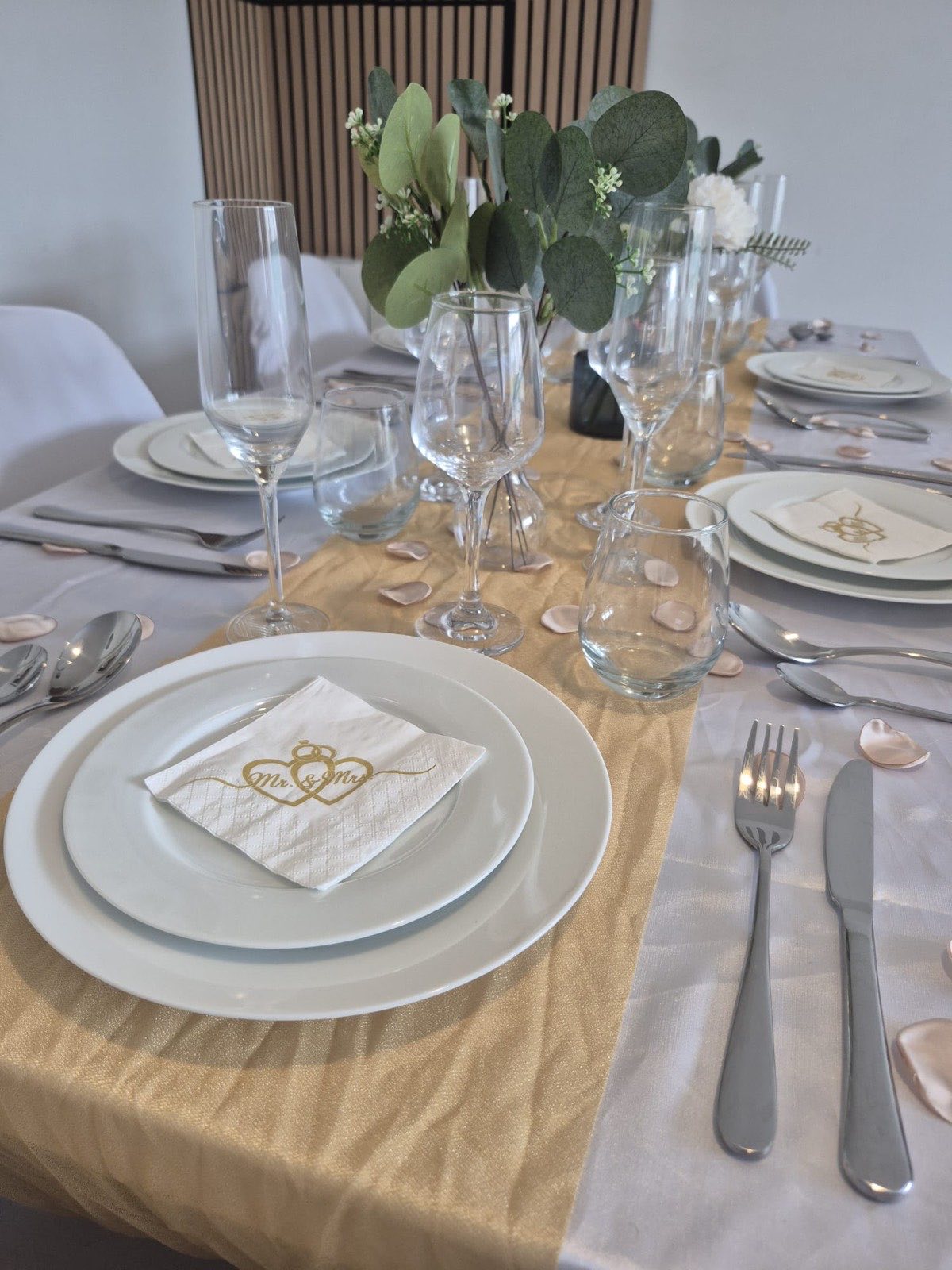 Couvert dressé avec assiettes blanches, verres à pied et couverts en inox
