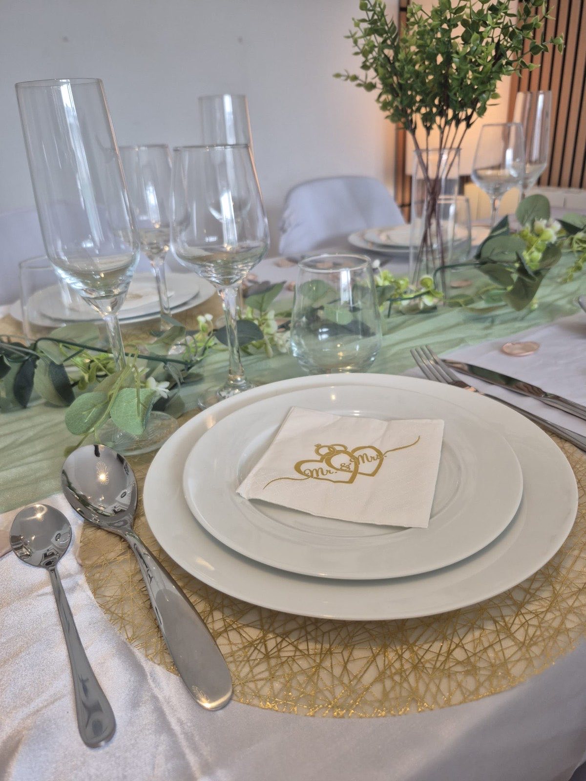 Couvert dressé avec assiettes blanches, verres à pied et couverts en inox