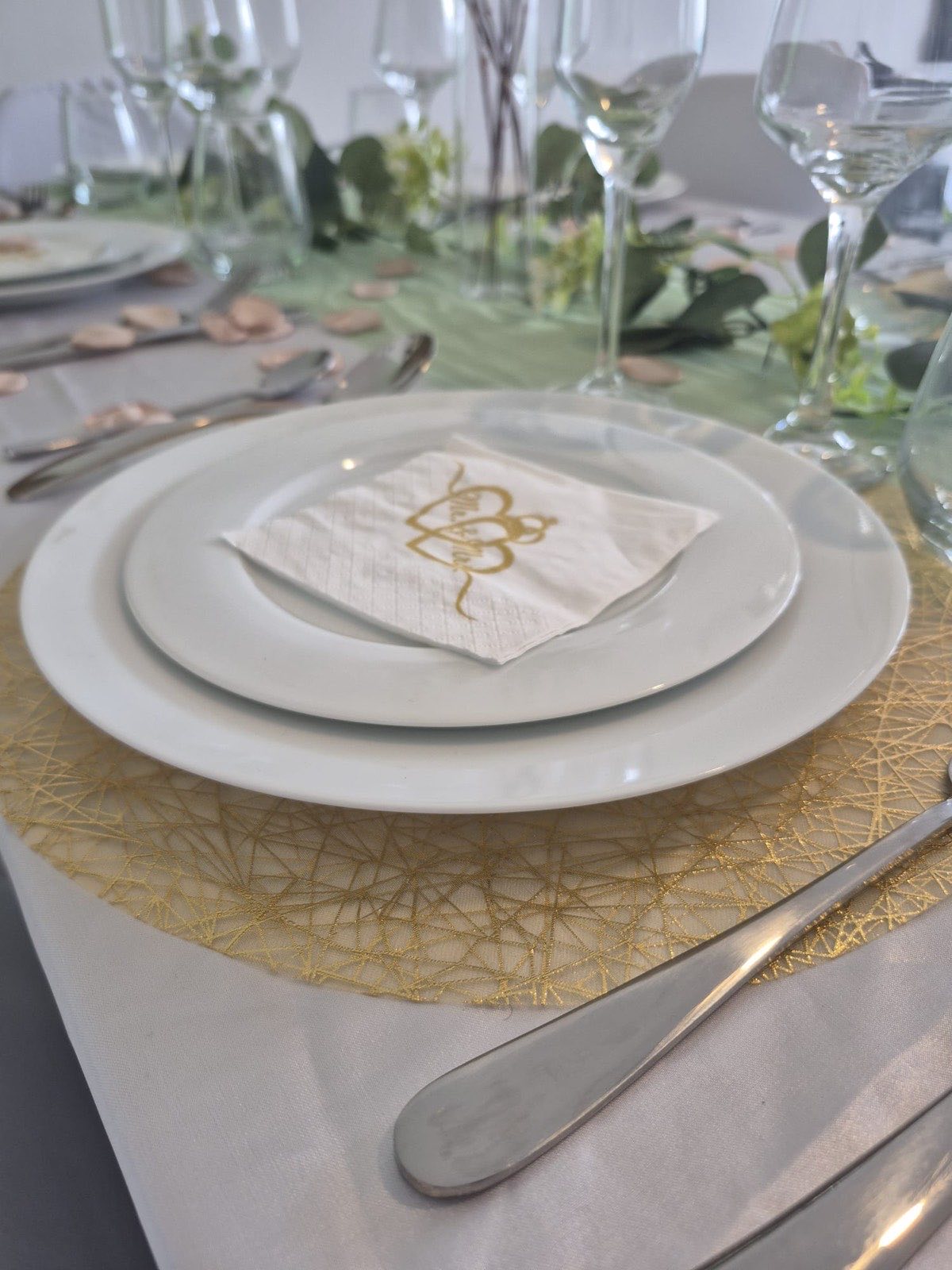Couvert dressé avec assiettes blanches et couverts en inox pour une réception